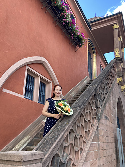 Die neue Kulturamtsleiterin Cornelia Lanz steht auf der Treppe vorm roten Alten Rathaus. Sie hat einen bunten Blumenstrauß in der Hand.