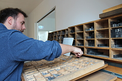 An einem Setzkasten zeigt ein Museumsmitarbeiter, wie früher Schrift gesetzt wurde. 