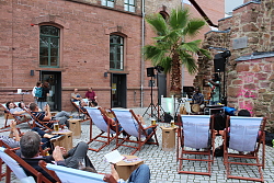 Liegestühle stehen auf dem Museumsplatz. Im Hintergrund ist das Stadtmuseum zu sehen. Rechter Hand die Bühne der Museumsbar.