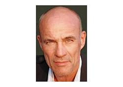 Ein Mann ohne Bart ist direkt in Großaufnahme portraitiert.