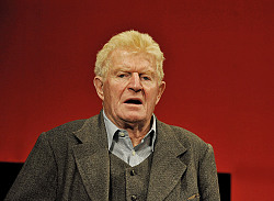 Schauspieler Peter Bause in Frontalaufnahme vor rotem Hintergrund.