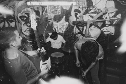 Schwarz-Weiß-Foto der Band KID-O mit Schlagzeug, Bass und zwei Gitarren in Aktion im Proberaum