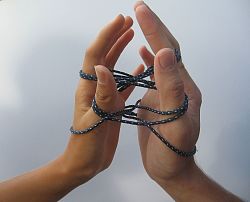 Es sind zwei Hände abgebildet. Die rechte und linke Hand einer Person, die nicht sichtbar ist. Um die Finger der Hände windet sich ein dicker blauer Faden mit weißen Pünktchen.