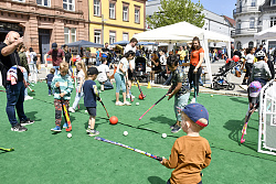 Bild vom Kinderfest in der Lahrer Innenstadt auf dem Rathausplatz. Es sind Kinder zu sehen die Hockey spielen auf einer Kunstrasenmatte. 