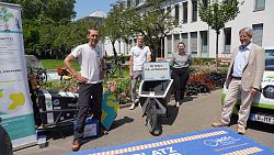 Anlässlich des Starts der Lahrer Klimawette stehen,&#13;&#10;von links nach rechts, der Initiator der Klimawette, Dr. Michael Bilharz, Martin Stehr vom Stadtplanungsamt, zuständig für Verkehr, Mobilität, Radwege, Pedelec-Verleihsystem und Rheintalbahn, die Lahrer Klimaschutzmanagerin, Madeleine Krol und Bürgermeister Tilman Petters im Rathausinnenhof zusammen. Im Hintergrund Fahrräder und Lastenräder, ein E-Auto und verschiedene Werbematerialien für die Klimawette.&#13;&#10;