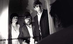 Schwarz-weiß Aufnahme. Kreidlinger, Bäuerle und Praktikantin Schmidt stehen in einem Türrahmen. Sie schauen entgeistert auf den Mann, der vor der Türe steht.