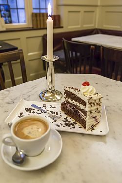 Großaufnahme einer Tasse Kaffee und einem leckeren Stück Schwarzwälder Kirschtorte an einem Tisch im Café Süßes Löchle