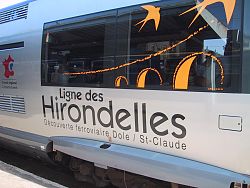 Das Bild zeigt einen silbernen Wagen des Schwalbenzugs bei Dole von außen. Auf dem Wage steht Ligne des Hirondelles.