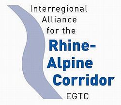 Das Bild zeigt des Logo des Verbunds Rhein-Alpen Korridor. Links ist in hellblau der Rhein angedeutet. Rechts steht in schwarz Interregional Alliance for the und darunter fettgedruckt in blau Rhine-Alpine Corridor und darunter ins schwarz EGTC.