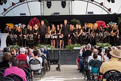 Orchester auf der E-Werk-Bühne stehend, alle Musiker sind in schwarz gekleidet. 