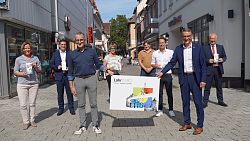 Die neue LahrCard präsentieren Martina Mundinger, Stadtmarketing, Florian Störk, Volksbank Lahr, Michael Schmiederer und Sarina Metzger, Werbegemeinschaft Lahr, Dieter Deninger und Ralph Friedrich, trolleymaker GmbH, Oberbürgermeister Markus Ibert und Klaus Bühler, Sparkasse Offenburg/Ortenau (von links). Sie stehen in der Fußgängerzone, und Michael Schmiederer und Markus Ibert halten eine überdimensional große Lahrcard in der Hand.
