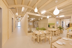 Innenraum mit heller Holzverkleidung und Kindermöbeln und Spielgeräten.