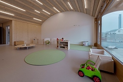 Innenraum mit heller Holzverkleidung und Kindermöbeln und Spielgeräten.