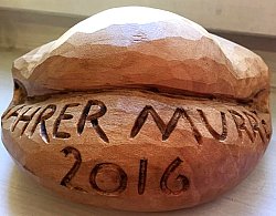 Auf dem Bild ist der Mundartpreis "Lahrer Murre" zu sehen. Er ist aus Holz geschnitzt und der Form nach dem Gebäck "Murre" nachempfunden. Im Holz ist der Schriftzug "Lahrer Murre 2016" eingeschnitzt.