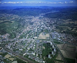 Das Bild zeigt eine Luftbildaufnahme von Lahr aus Richtung Westen. Zu erkennen sind die Kernstadt und dahinter die beiden Stadtteile Kuhbach und Reichenbach im Tal zwischen Schwarzwaldbergen.