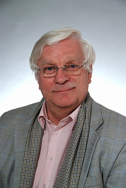 Passbild des grauharigen Maurizio Poggio mit grauem Anzug, der in die Kamera lächelt. 