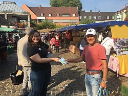 Klimaschutzmanagerin Madeleine Krol überreicht Wilfried Walter auf dem Lahrer Wochenmarkt ein Klimasparbuch