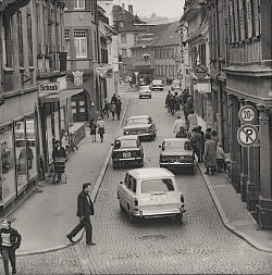 Die marktstraße der Statd Lahr auf einer schwarz-weiß Fotografie aus dem Jahr 1966. Es herrscht recht viel Verkehr und auch Fußgänger sind unterwegs.
