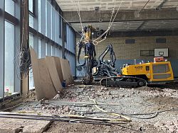 Aus dem Bild ist eine große gelbe Maschine in einem Raum des Max-Planck-Gymnasiums zu sehen. Auf dem Boden liegen Bauschutt und Kabel.