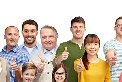 Eine Gruppe verschiedener Personen mit verschiedenen Hautfarben, in unterschiedlichem Alter, steht zusammen und hält lachend den Daumen hoch in die Kamera.