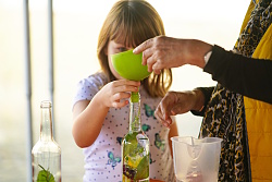 Das Foto zeigt ein Kind beim Abfüllen von Öl in eine Flasche