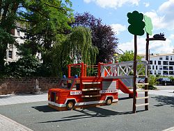 Auf dem Rathausplatz in Lahr steht ein neues Spielgerät für Kinder. Ein großes Feuerwehrauto, in und auf dem man wild spielen kann. Dazu gehört ein Baum aus Holz, auf dem sich eine schwarze Katze befindet.