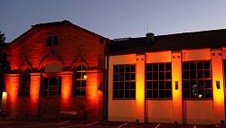 Der Schlachthof Jugend & Kultur in Lahr, am Abend, mit roten Scheinwerfern angestrahlt.