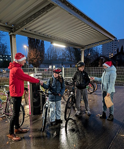 Mann im Nikolauskostüm überreicht Schülerinnen und Schülern mit Fahrrädern kleine Geschenke.