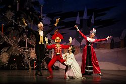 Tänzerinnen und Tänzer mit Masken und historischen Kostümen vor einem Weihnachtsbaum