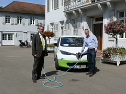 Vor dem Rathaus steht das E-Mobil des Car-Sharings. Umweltbeauftragter Manfred Kaiser steckt den Stecker des Ladekabels in das Auto, Bürgermeister Tilman Petters hält das andere Ende. Beide lächeln in die Kamera. 
