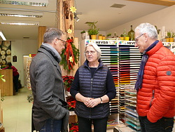 Das Bild zeigt zwei Männer und eine Frau, die im Gespräch in einem Geschäft sind. Bei den beiden Männern handelt es sich um Oberbürgermeister Ibert und Ortsvorsteher Girstl, die Frau ist Geschäftsinhaberin Fleig