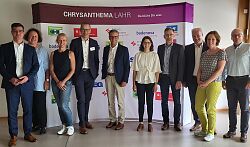 Vertreterinnen und Vertreter der Sponsoren und der Stadtverwaltung stehen vor einer Plakatwand zur Chrysanthema 2023.