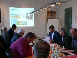Auf dem Bild ist das Sitzungszimmer im Rathaus 1 in Lahr zu sehen. An einem großen Holztisch sitzen Medienvertreter, Oberbürgermeister Dr. Müller, Markus Ibert und Arnfried Sickinger. Ein Beamer wirft eine Präsentation zum Güterverkehrsterminal an die Wand.