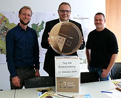 Bei der Pressekonferenz zur Vorstellung des Programms am Tag der Entscheidung zum Lahrer Stadtgulden zusammen mit dem zwölften Lahrer Suppenfest: Jakob Crone, Erster Bürgermeister Guido Schöneboom und Andreas May stehen vor einer Stadtgulden-Wahlurne. Schöneboom hält einen übergroßen Lahrer Stadtgulden über die Urne.