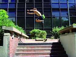 Der Schlachthof Jugend & Kultur Lahr bietet einen Parkour-Workshop. Hier springt ein Parkour-Künstler über eine Treppe im Freien, von rechts nach links, von Mauer zu Mauer. 