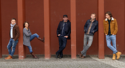 Fünf Musikerinnen und Musiker zwischen roten Säulen