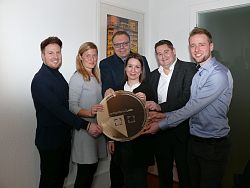 Auf dem Foto von links nach rechts: Pierre Grieger von der Agentur Vollblutwerber, Senja Töpfer, Leiterin des Amts für Soziales, Schulen und Sport, Erster Bürgermeister Guido Schöneboom, Jessica Schwarz und Malte C. Bayer von der Agentur Vollblutwerber sowie Jakob Crone, verantwortlich bei der Stadt Lahr für das Projekt Stadtgulden, Die Personen zeigen gemeinschaftlich einen übergroßen Stadtgulden in die Kamera. Er soll zeigen wie die Münzen für die Abstimmung später aussehen werden.