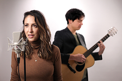 Auf dem Foto sind zwei Menschen zu sehen. Er spielt Gitarre und sie singt 