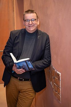 Das Foto zeigt den Autor Michael Paul. Er hält seinen neuen Roman "Versteckt im Schwarzwald" in seiner Hand.