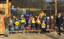 Die Kinder der Kita Kuhbach stehen im Außengelände, aufgereit zu einem Gruppenbild. Die Kids tragen teilweise das Stapelset. 