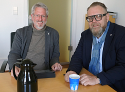 Zwei Männer an einem Tisch mit Tasse und Kaffeekanne