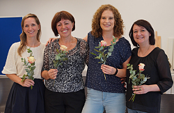 Erfolgreiche Quereinsteigerinnen stehen mit einer Rose in der Hand von links: Judith Schmidt, Natalia Reschetnik, Ines Feudel und Rinita Hald-Stukert.