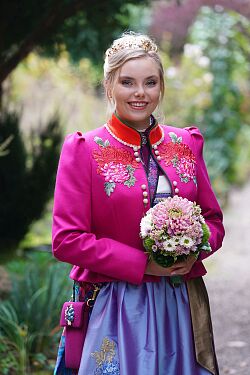 Die Chrysanthemenkönigin Juliane II präsentiert sich in ihrem Gewand und hält einen Strauß mit Chrysanthemen.