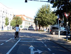 Ein Radfahrer steht auf einem Schutzstreifen wartend an einer roten Ampel