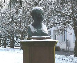 Bronzebüste eines Mannes mit leicht welligem Haar.