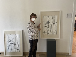 Die Künstlerin Renate Henningen steht zwischen zwei Zeichnungen im Lahrer Rathaus 1.