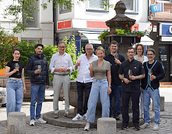 Auf dem Bild sind verschiedene Menschen aus der Gastronomie mit dem OB zusehen, wie sie am Rosenbrunnen anstoßen.