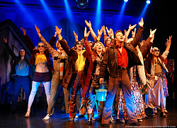 Zwölf Tänzerinnen und Tänzer in Pfeilformation strecken die Ärme in die Höhe wie bei typischen Tanzschritten Ende der 70er Jahre.