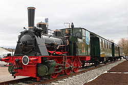 Ein historischer Dampfzug macht auf dem Gelände der Landesgartenschau Lahr Halt. Das Bild zeigt einen historischen Dampfzug mit Logs und Waggons in grün. 