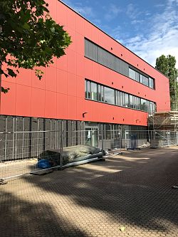 Ziegelrote Fassade des Scheffel-Gymnasiums mit einem Bauzaun